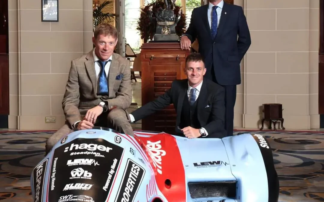 Three men stood by a race car
