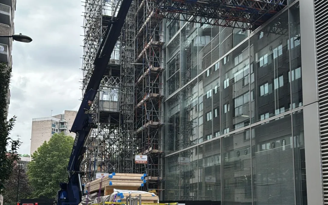 Crane lifting panels next to glass building