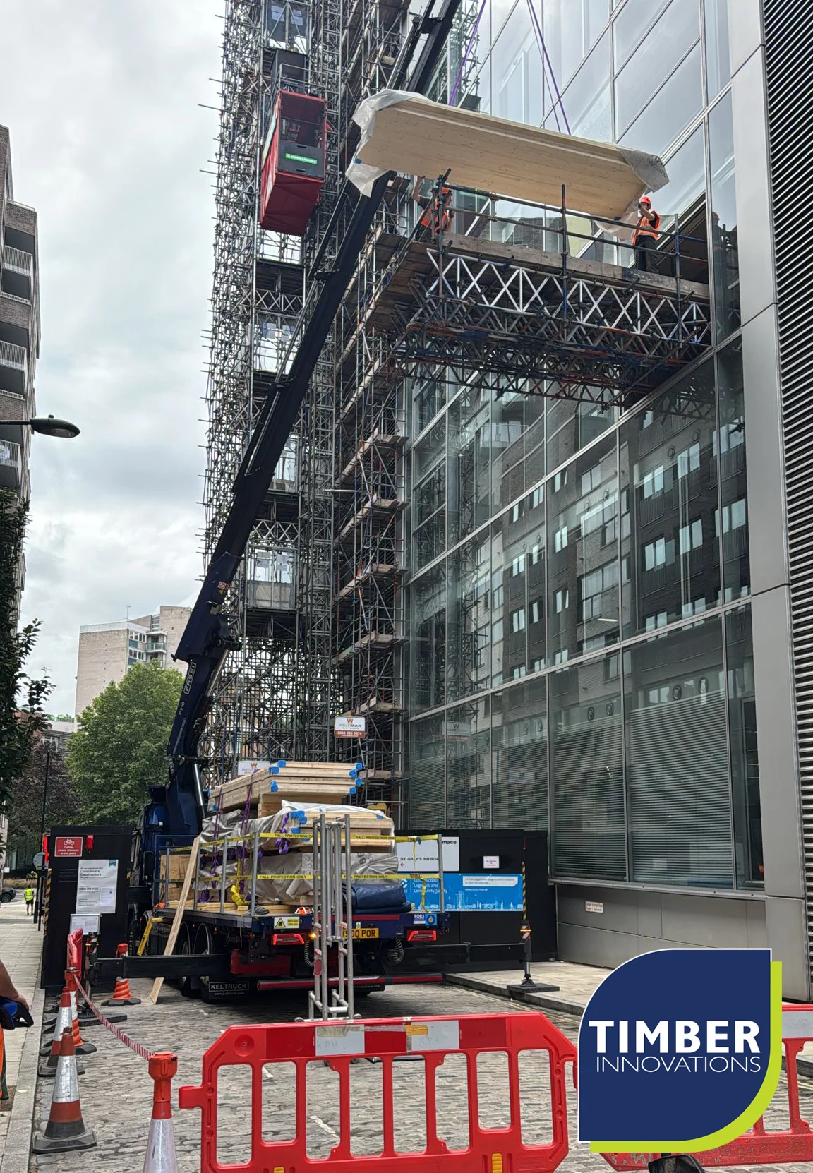 Crane lifting panels next to glass building