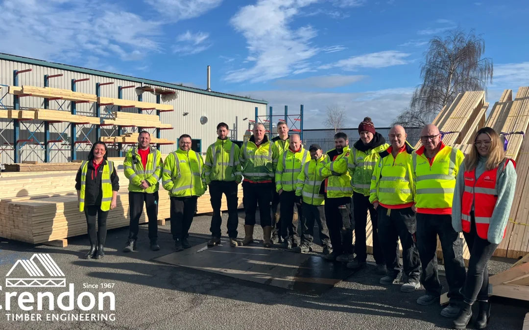 Team photo with everyone wearing hi vis jackets surrounded by timber