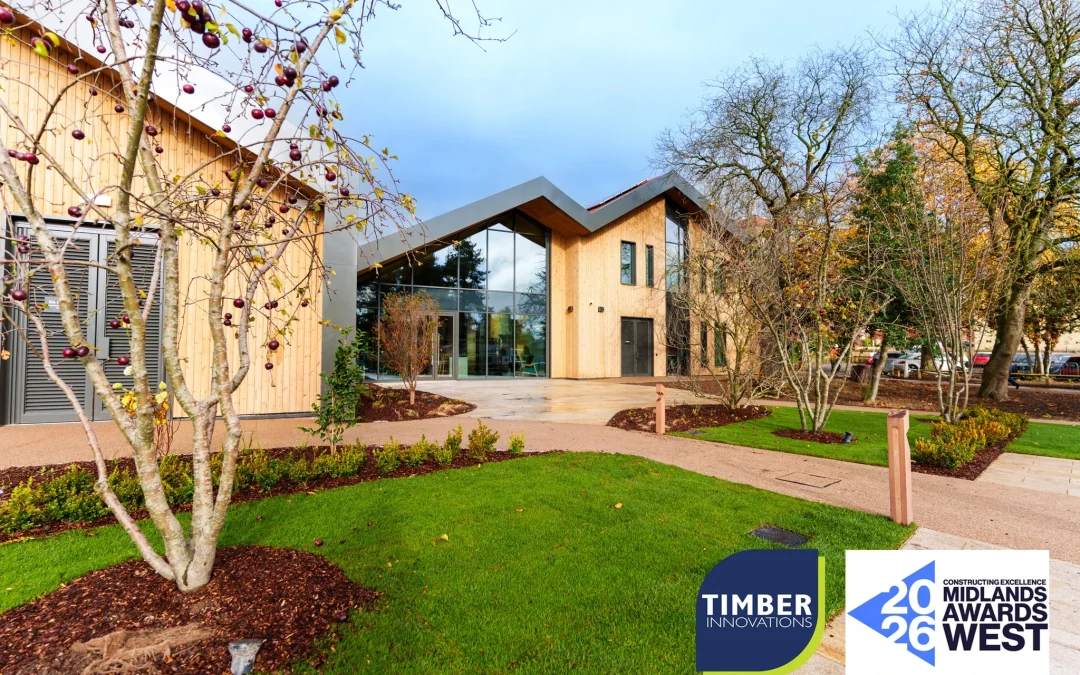 Building with wooden panels from top to bottom with windows floor to ceiling surrounded by patches of grass and trees