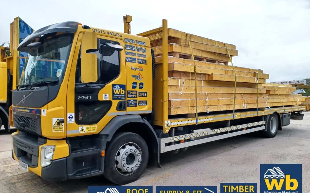 Yellow Wyckham Blackwell lorry with piles of timber on the back