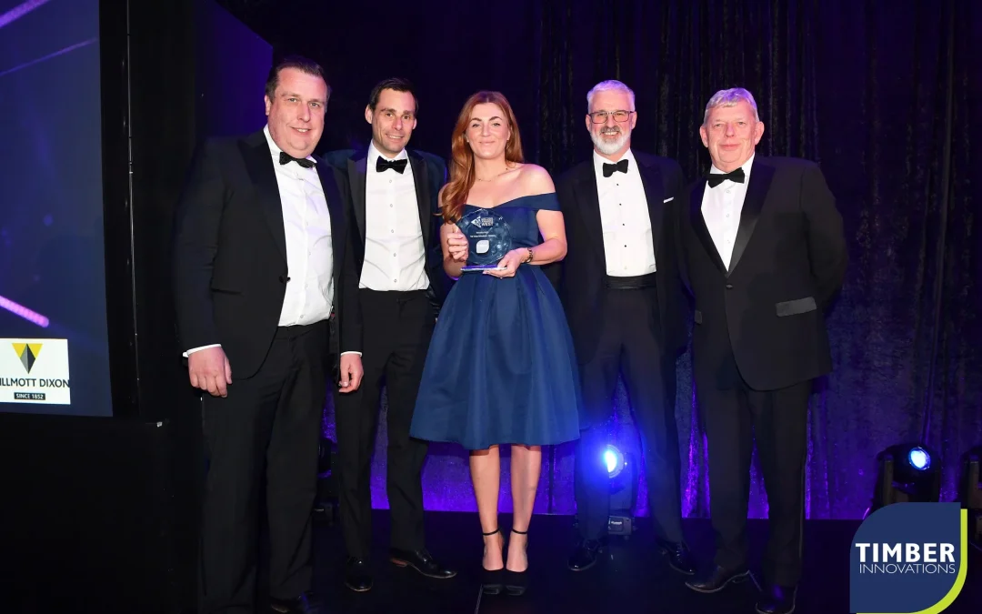 4 men in suits and 1 woman in a blue dress standing on a stage holding a trophy