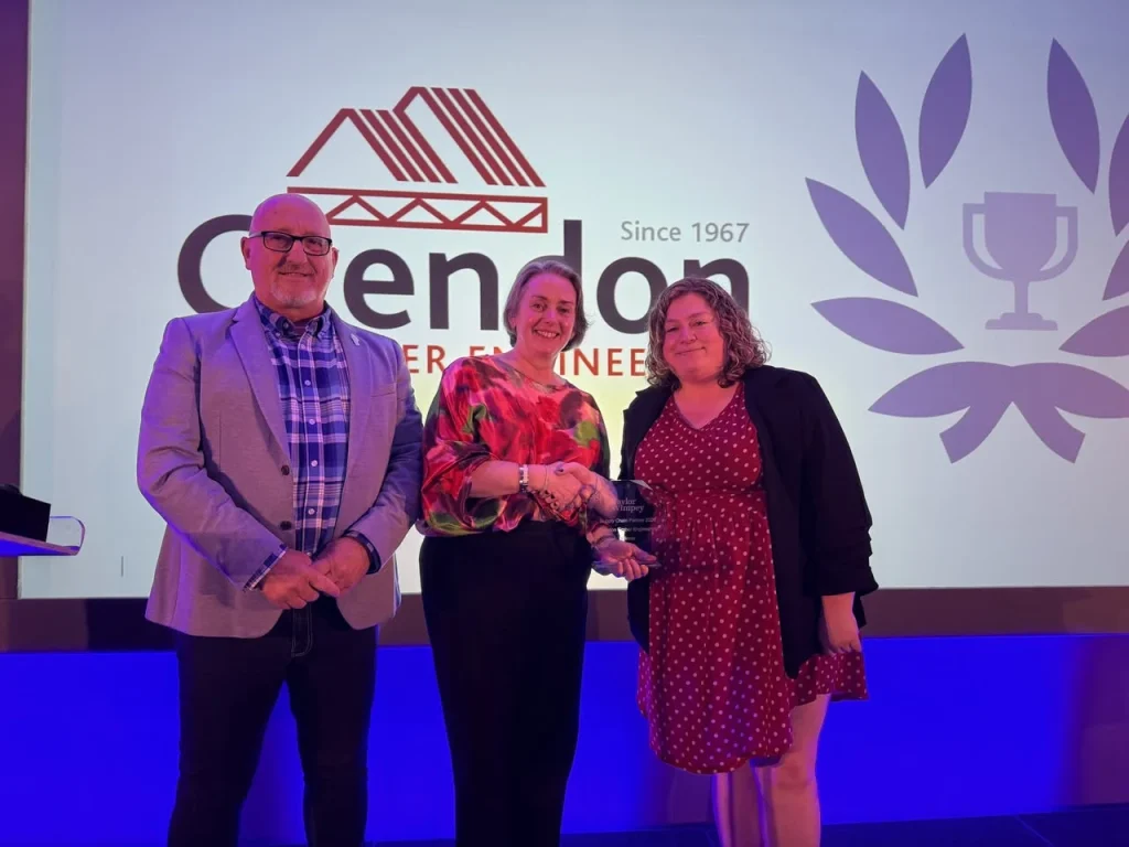 A man and 2 women stood with trophy in front of Crendon screen