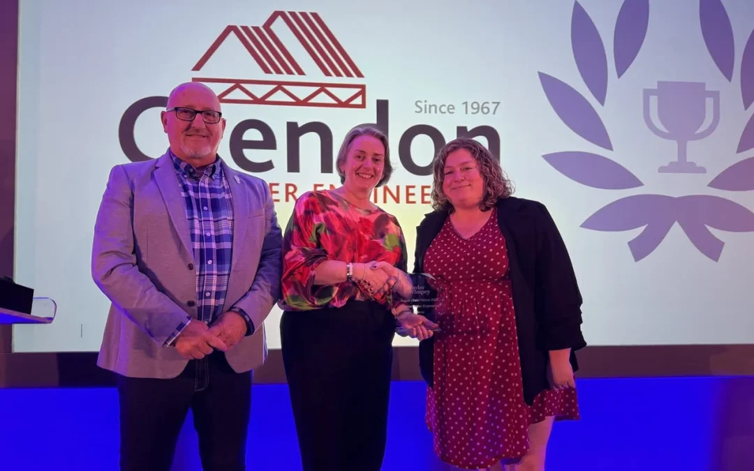A man and 2 women stood with trophy in front of Crendon screen