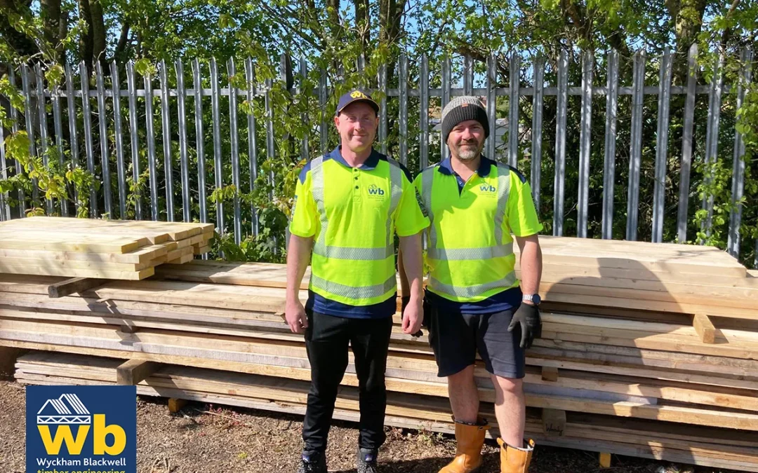 2 men in Wyckham Blackwell hi vis jackets standing in front of a pile of timber