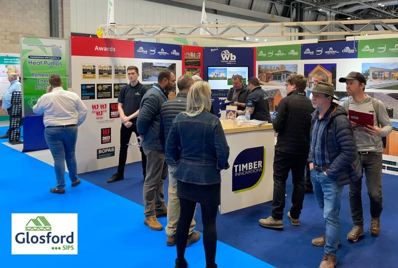 Busy exhibition booth for Timber Innovations/Glosford SIPS with staff and visitors discussing product displays and awards.