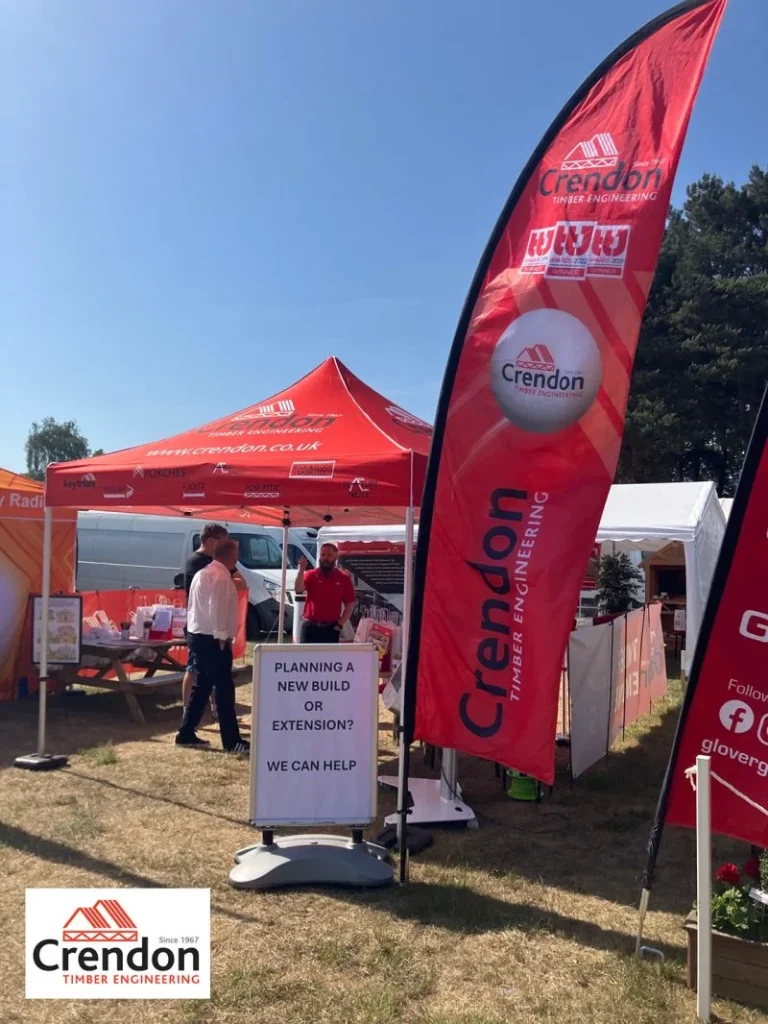 Crendon Timber Engineering red booth and flag at The Suffolk Show, staff by sign offering help with new builds or extensions.