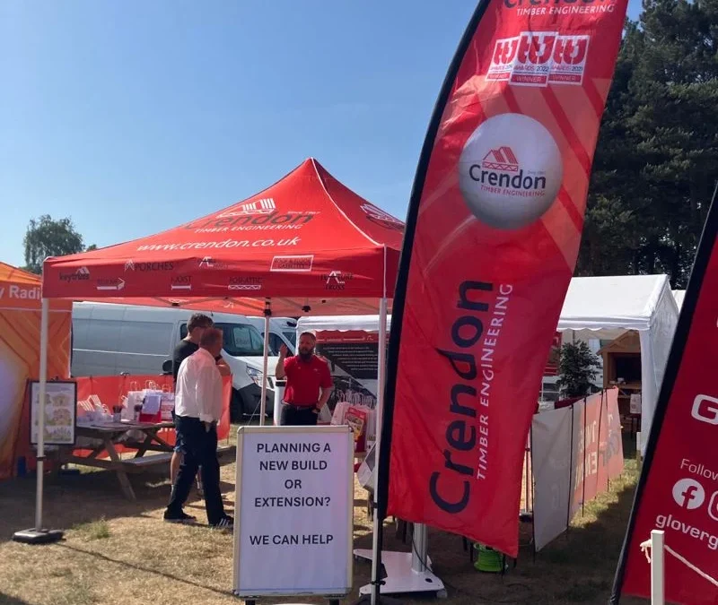Crendon Timber Engineering red booth and flag at The Suffolk Show, staff by sign offering help with new builds or extensions.