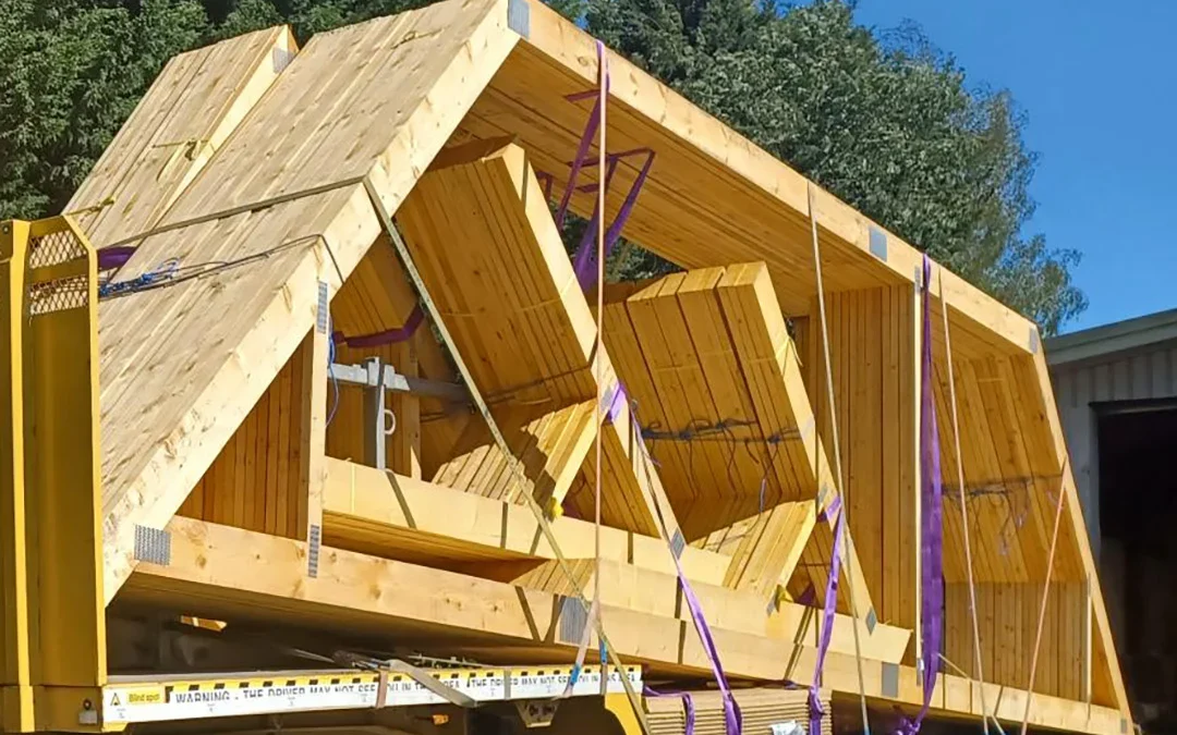Yellow Wyckham Blackwell flatbed lorry with timber roof truss strapped on the back