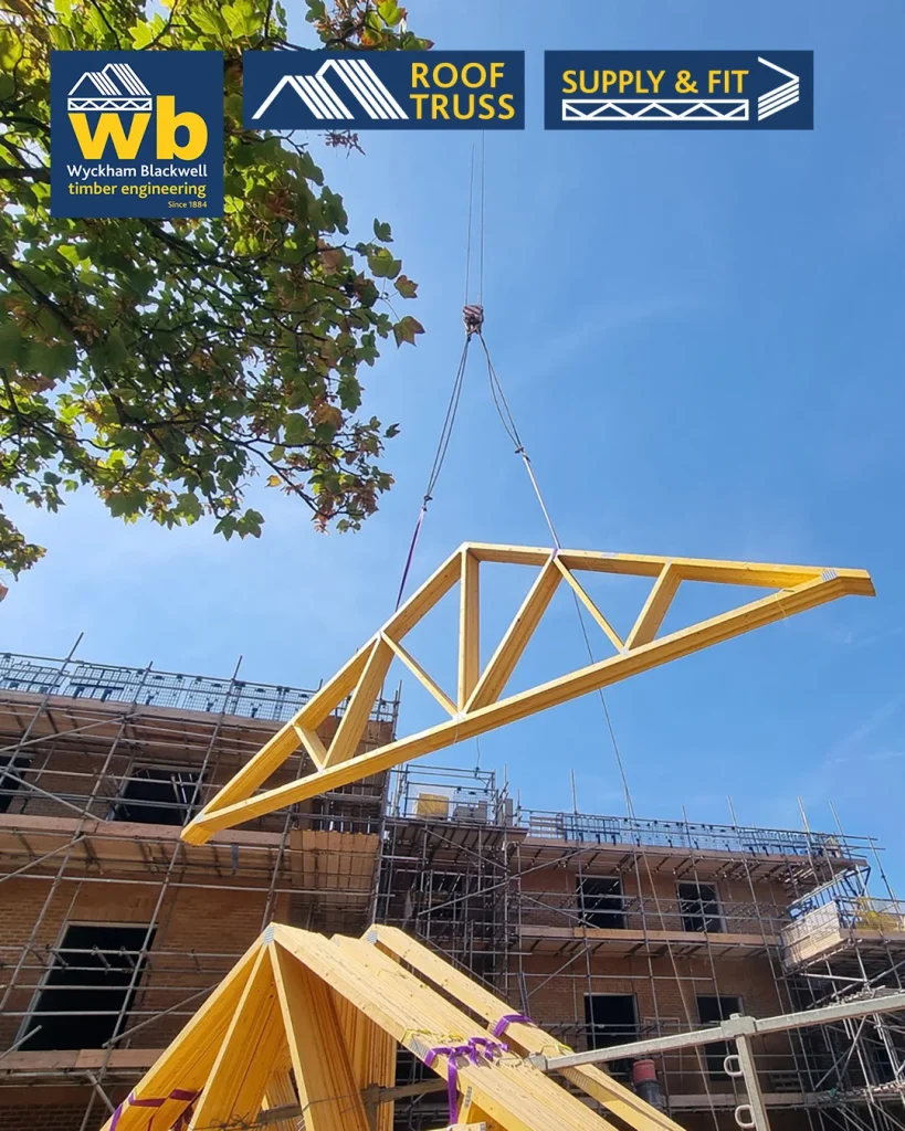 Timber Roof Truss lifted by crane above scaffolding at a construction site, with Wyckham Blackwell logo top left.